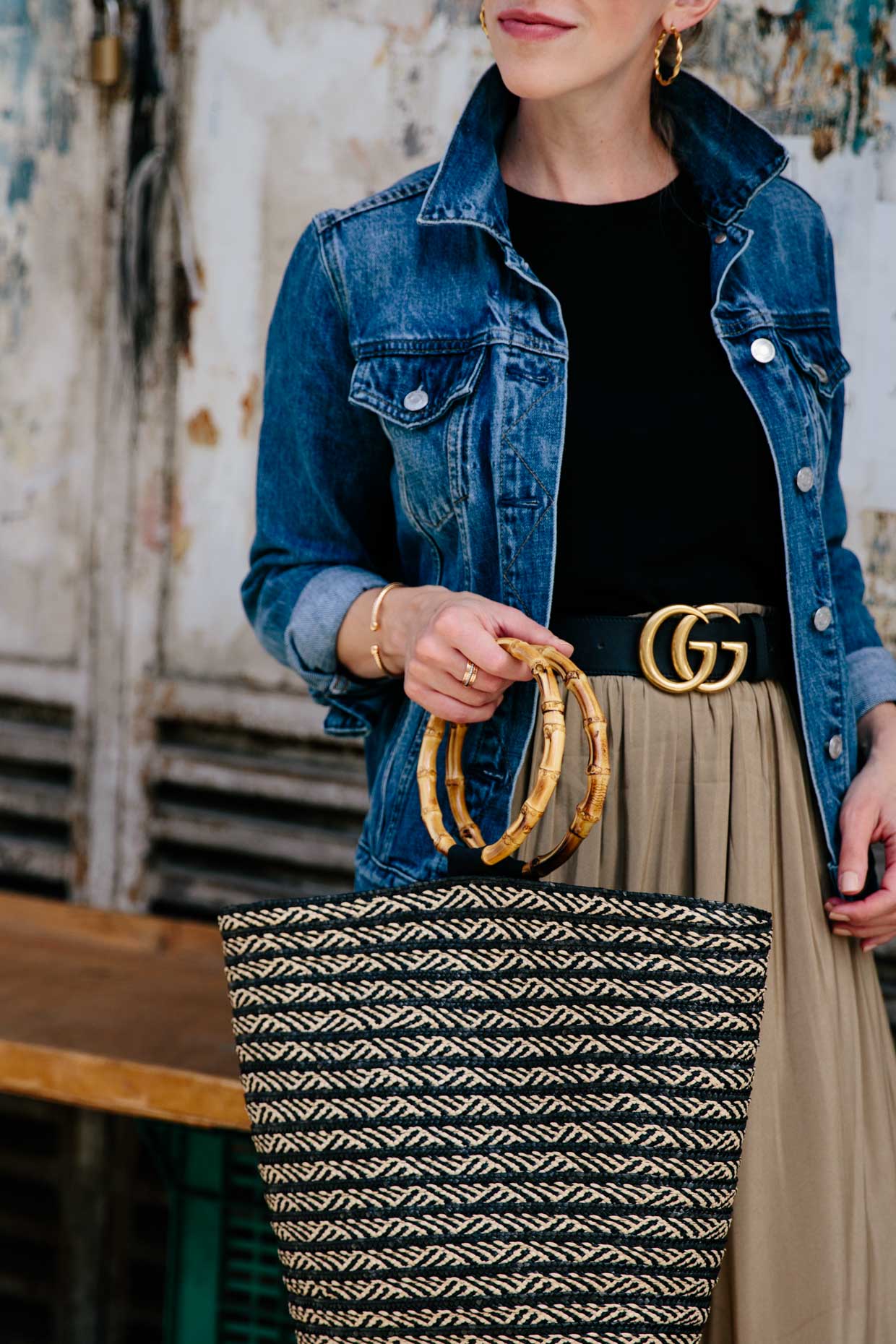 Meagan Brandon Fashion Blogger Of Meagan S Moda Wears Denim Jacket With Gucci Belt Pleated Skirt And Bamboo Handle Straw Tote Bag For Transitional Summer To Fall Outfit Idea Meagan S Moda