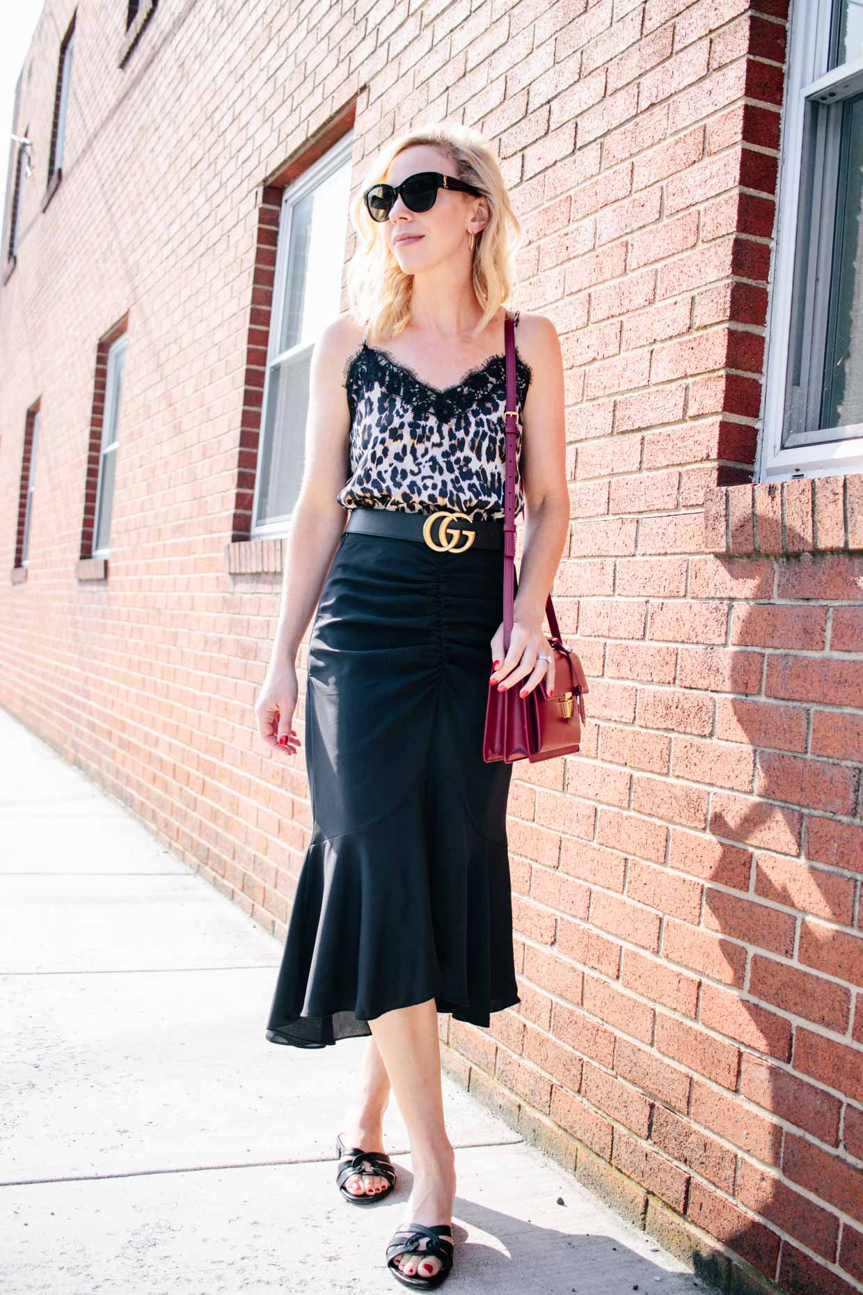 Meagan Brandon fashion blogger of Meagan's Moda shows leopard print  camisole outfit with black fluted midi skirt and red Saint Laurent high  school satchel - Meagan's Moda